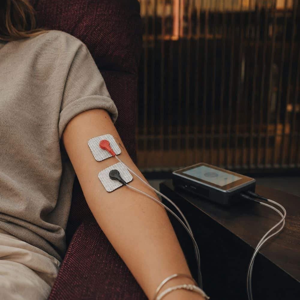 Zwei Elektroden auf einem Unterarm, daneben das MicuFlow-Gerät